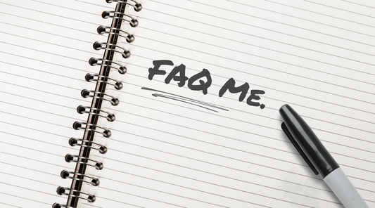 "FAQ Me." is written in black marker on a white lined notebook. A black Sharpie pen sits next to the text.